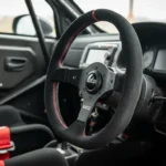 Volant de rallye Sparco compact dans un cockpit de compétition avec harnais FIA